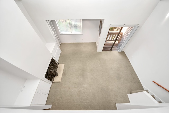 unfurnished living room with carpet flooring, a healthy amount of sunlight, stairway, and baseboards