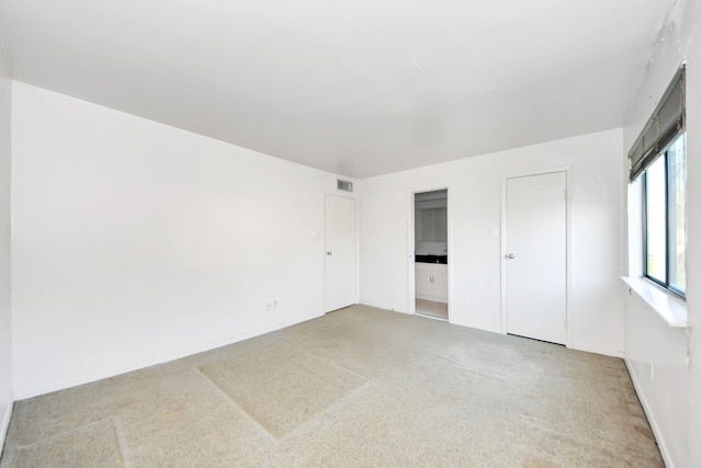 unfurnished bedroom with light carpet and visible vents