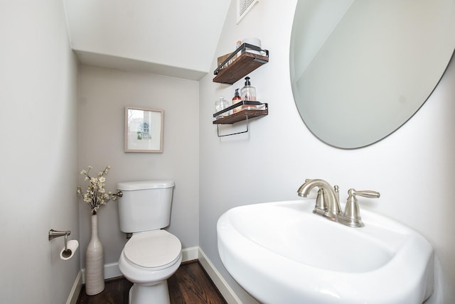 bathroom featuring visible vents, toilet, a sink, wood finished floors, and baseboards