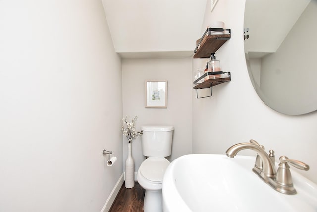 bathroom with toilet, wood finished floors, baseboards, and a sink