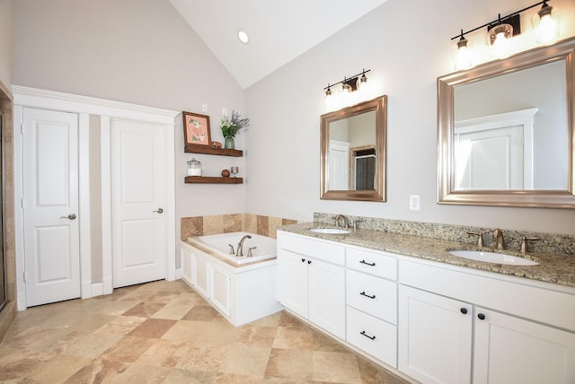 bathroom with lofted ceiling, a bath, double vanity, and a sink