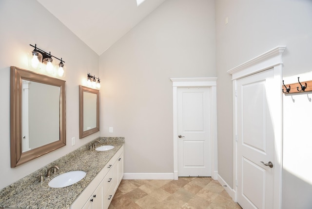 bathroom with vaulted ceiling, double vanity, baseboards, and a sink