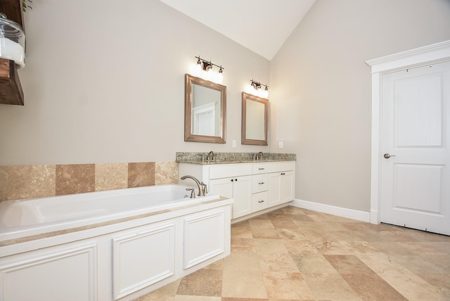 bathroom with baseboards, vanity, a garden tub, and vaulted ceiling