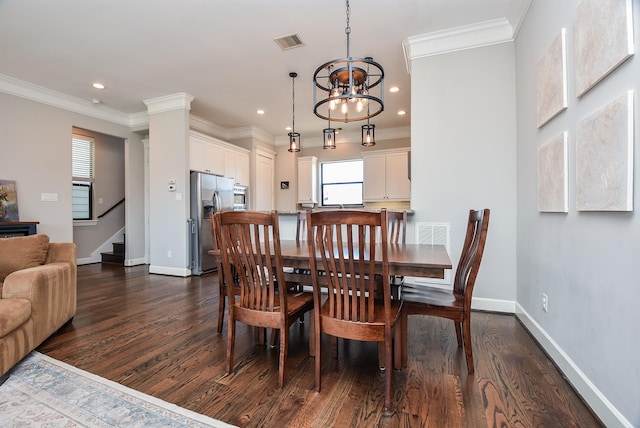 dining area with visible vents, dark wood-type flooring, baseboards, ornamental molding, and an inviting chandelier