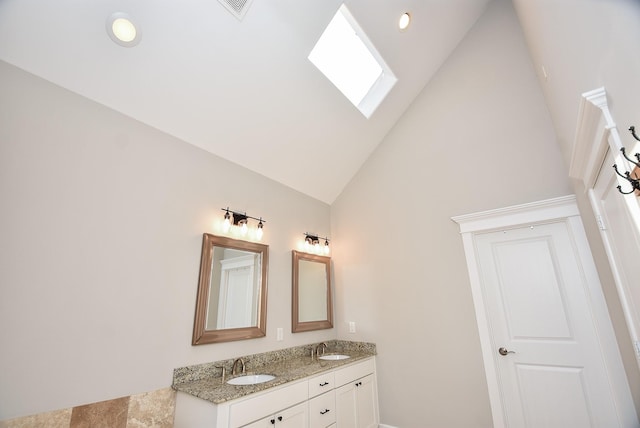 bathroom with double vanity, a skylight, high vaulted ceiling, and a sink