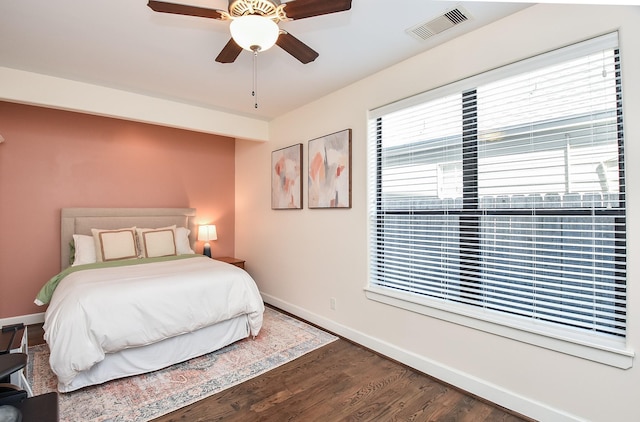 bedroom featuring visible vents, ceiling fan, baseboards, and wood finished floors