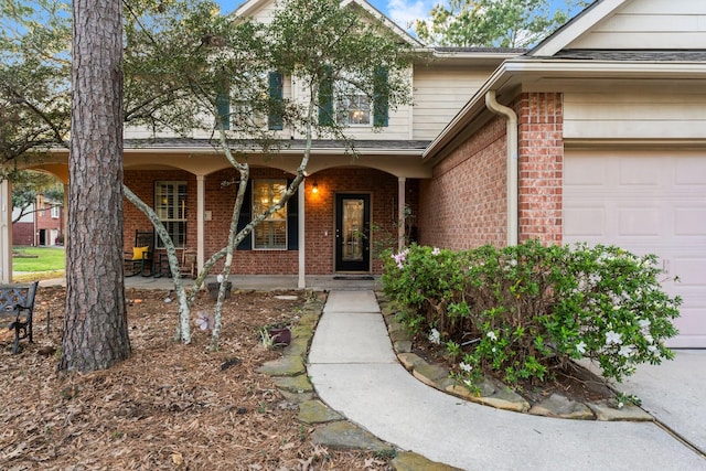 view of exterior entry with brick siding, covered porch, and a garage