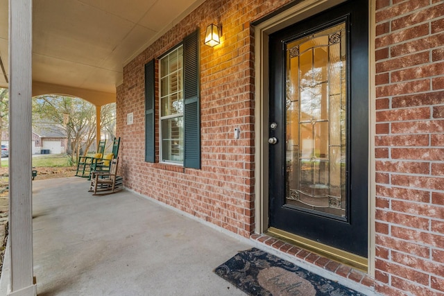 property entrance with a porch and brick siding