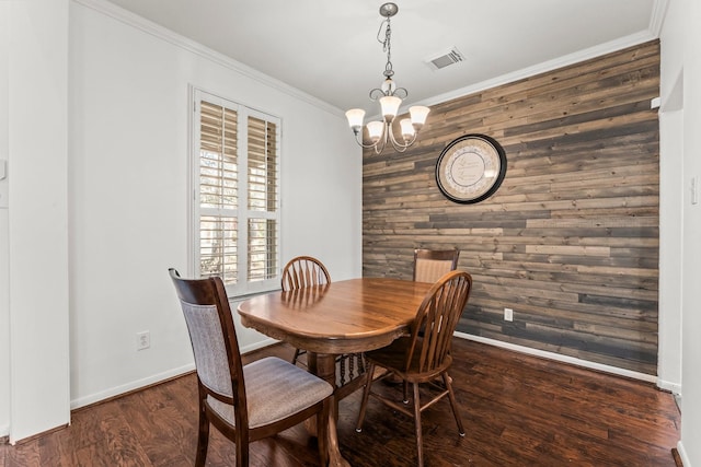 dining room with visible vents, wood finished floors, crown molding, a chandelier, and an accent wall