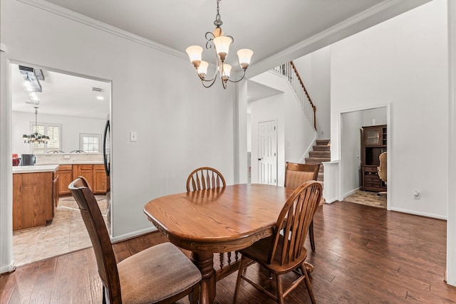 dining room featuring hardwood / wood-style flooring, stairway, baseboards, and a chandelier