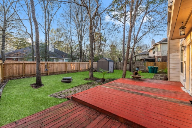 wooden terrace featuring an outbuilding, a lawn, a storage unit, and a fenced backyard