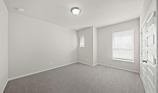 carpeted spare room featuring baseboards