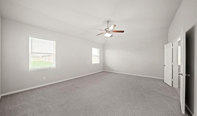 carpeted empty room featuring ceiling fan, lofted ceiling, and baseboards