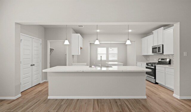 kitchen featuring a sink, stainless steel appliances, backsplash, and light wood finished floors