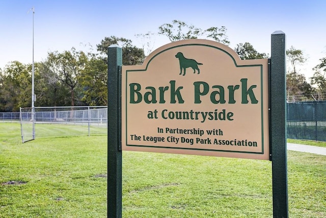 community / neighborhood sign with fence and a lawn