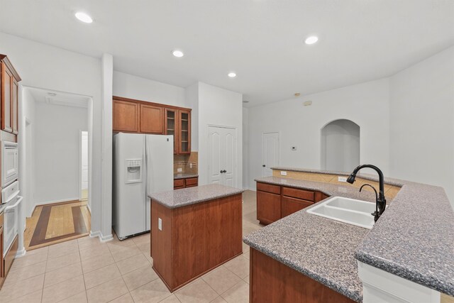 kitchen with a spacious island, light tile patterned floors, recessed lighting, white appliances, and a sink