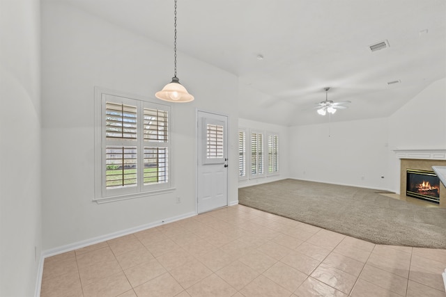 unfurnished living room featuring a wealth of natural light, a fireplace with flush hearth, light colored carpet, and visible vents