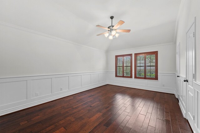 spare room featuring lofted ceiling, ornamental molding, wainscoting, a ceiling fan, and dark wood-style flooring