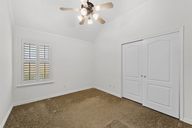 unfurnished bedroom featuring lofted ceiling, ornamental molding, a closet, dark colored carpet, and baseboards