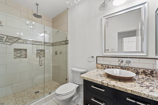 bathroom with vanity, a shower stall, toilet, and tasteful backsplash