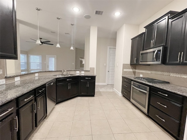 kitchen with visible vents, light stone counters, dark cabinetry, stainless steel appliances, and a sink