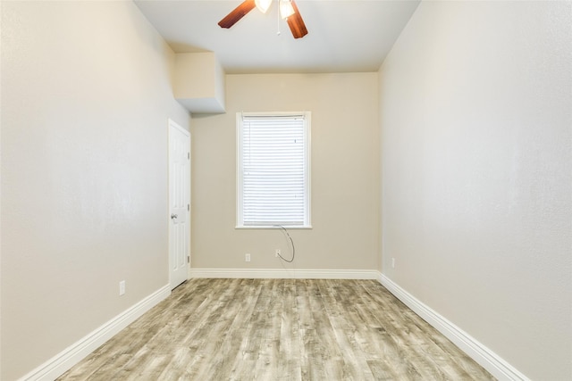 spare room featuring light wood-style flooring, a ceiling fan, and baseboards