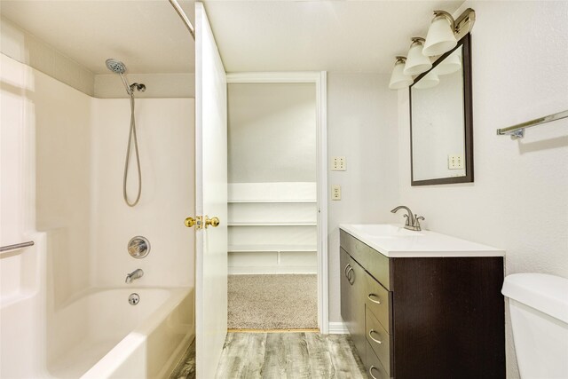 bathroom with toilet, vanity, shower / bathtub combination, and wood finished floors