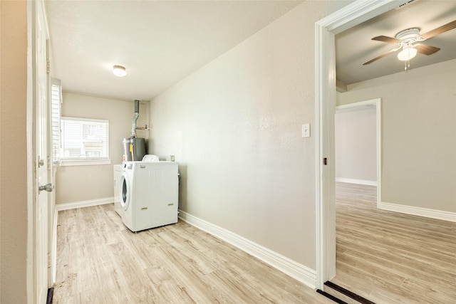 clothes washing area featuring baseboards, laundry area, light wood-style flooring, gas water heater, and washing machine and dryer