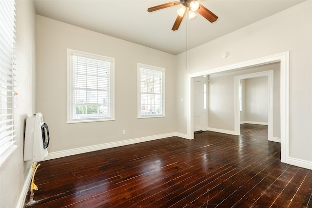 spare room with ceiling fan, dark wood-type flooring, and baseboards