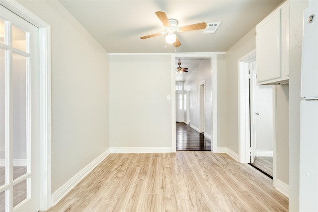 empty room with light wood finished floors, visible vents, ceiling fan, and baseboards