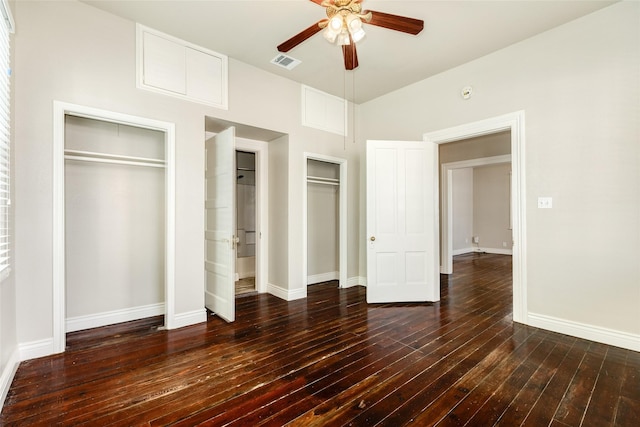unfurnished bedroom with visible vents, two closets, baseboards, hardwood / wood-style floors, and a ceiling fan