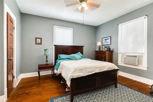 bedroom featuring cooling unit, baseboards, a textured ceiling, and wood finished floors