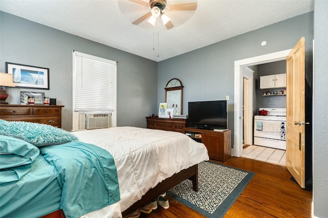 bedroom with a ceiling fan, cooling unit, wood finished floors, and a textured ceiling