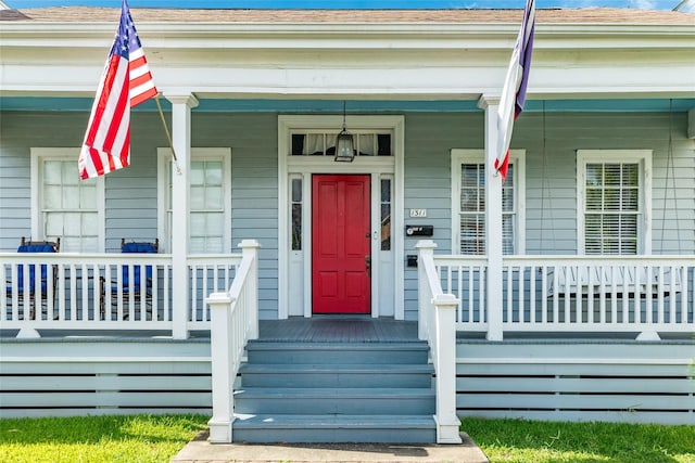 entrance to property with roof with shingles and covered porch
