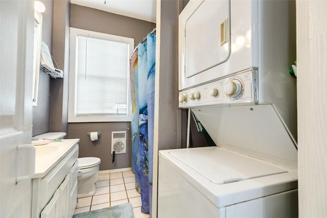 clothes washing area featuring light tile patterned floors, stacked washer / dryer, and laundry area