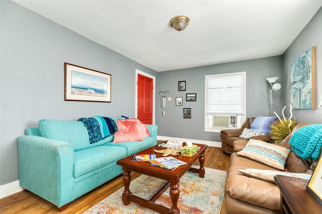 living area with cooling unit, wood finished floors, and baseboards