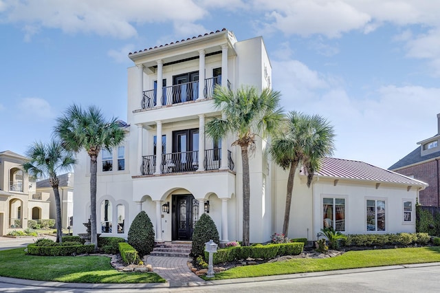 mediterranean / spanish-style home featuring a balcony, a standing seam roof, stucco siding, french doors, and metal roof