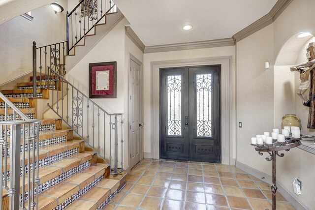 entrance foyer with light tile patterned floors, french doors, baseboards, and ornamental molding