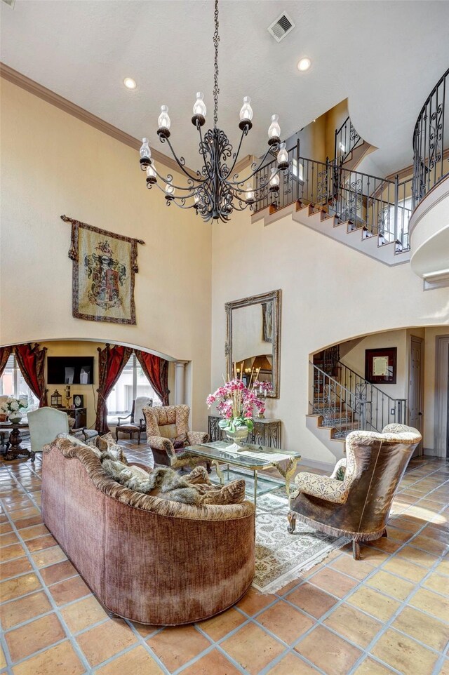 living room with visible vents, a towering ceiling, ornamental molding, and stairway