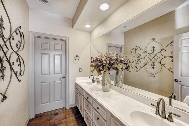 full bath with a sink, visible vents, wood finished floors, and double vanity