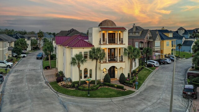 view of front of property with a residential view, stucco siding, metal roof, and a balcony