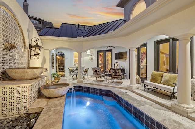 outdoor pool with decorative columns, arched walkways, and a hot tub