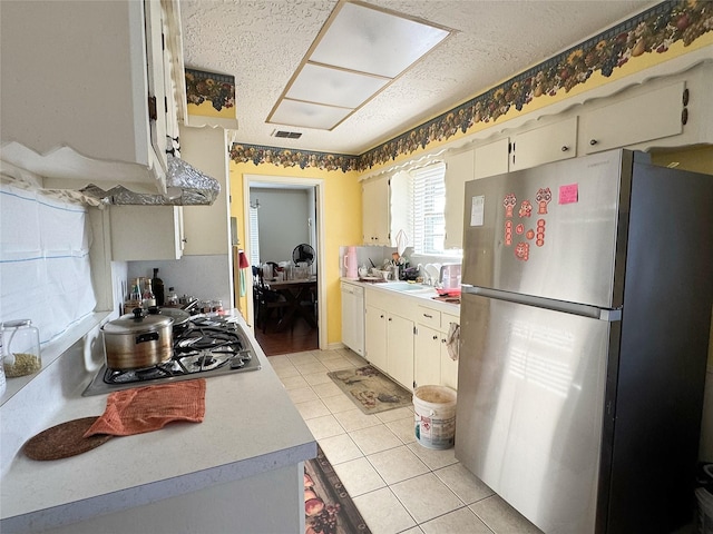 kitchen with visible vents, a textured ceiling, appliances with stainless steel finishes, light countertops, and light tile patterned floors