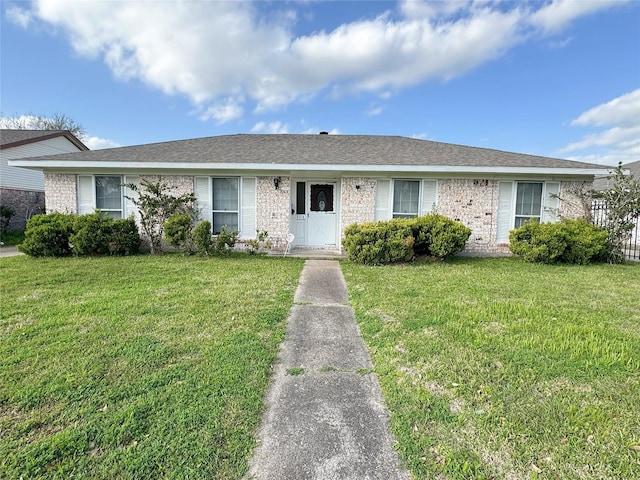 single story home featuring brick siding, a shingled roof, and a front lawn