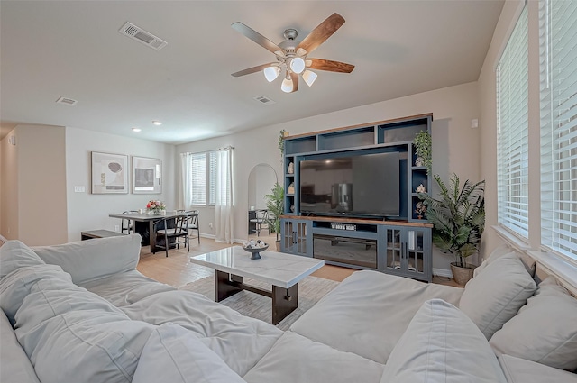 living area featuring visible vents, light wood-style flooring, baseboards, and ceiling fan