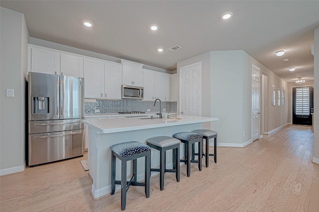 kitchen featuring visible vents, appliances with stainless steel finishes, light wood-style floors, white cabinetry, and a sink