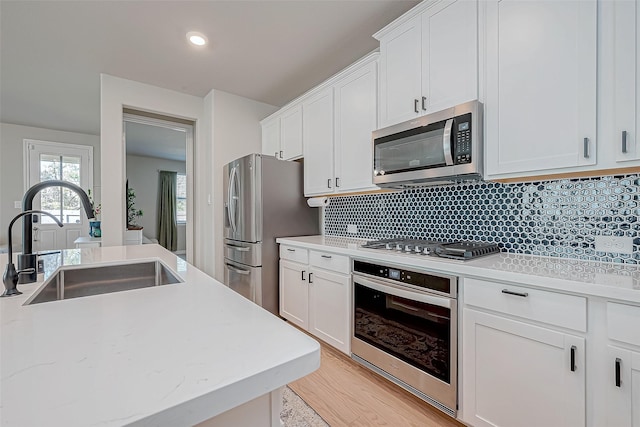 kitchen featuring a sink, tasteful backsplash, appliances with stainless steel finishes, and white cabinets