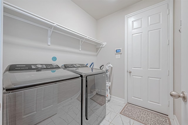 washroom featuring baseboards, marble finish floor, laundry area, and washer and clothes dryer