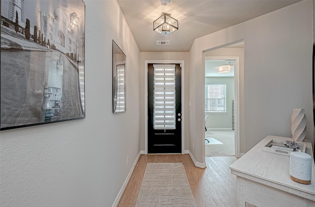 foyer entrance with wood finished floors, visible vents, and baseboards