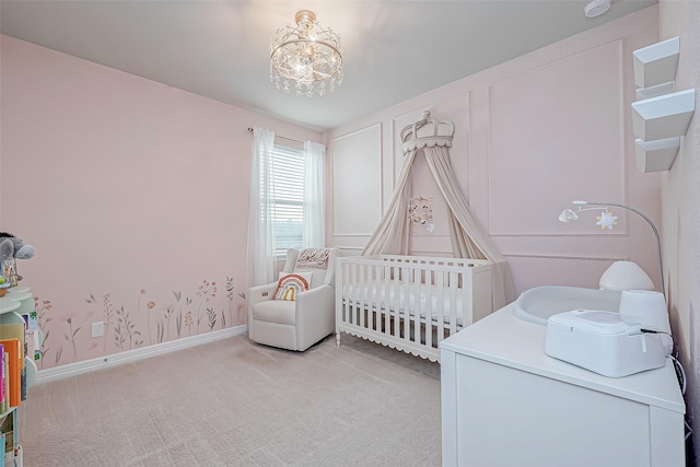 bedroom featuring baseboards, a crib, light colored carpet, and an inviting chandelier